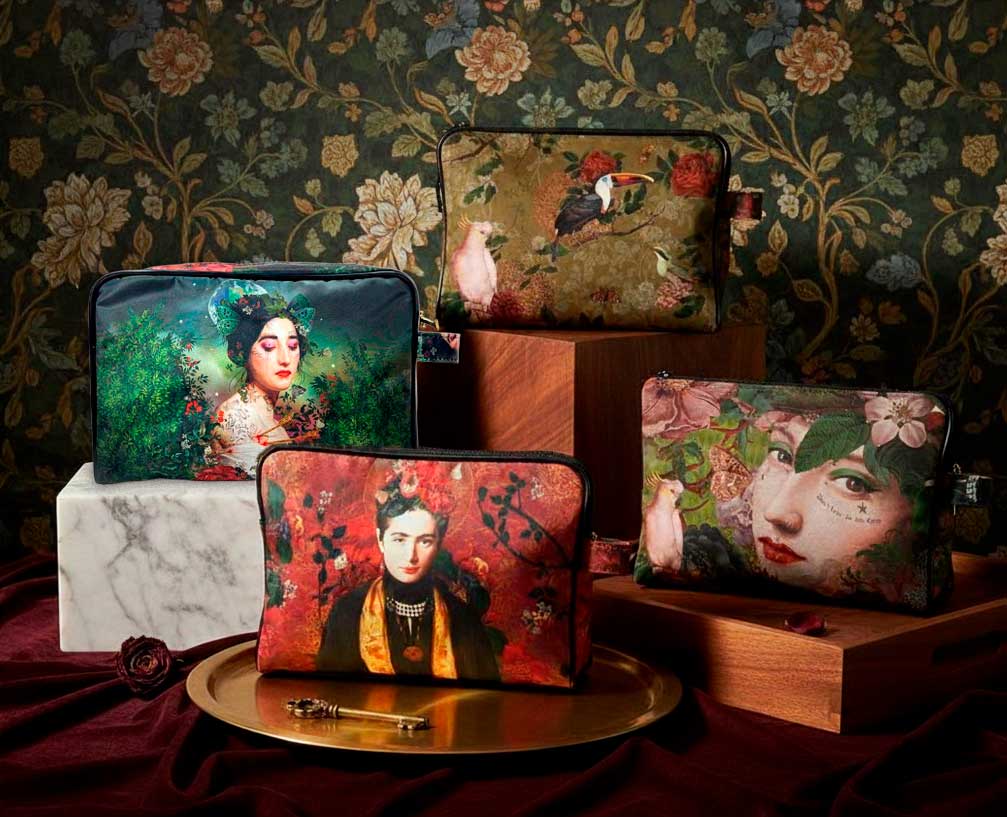 Kunstvolle Schminktäschchen von Voglio Bene mit ikonischen Portrait- und Blumenmotiven, stilvoll arrangiert vor floraler Tapete – elegante Beauty-Accessoires für Alltag und Reise.