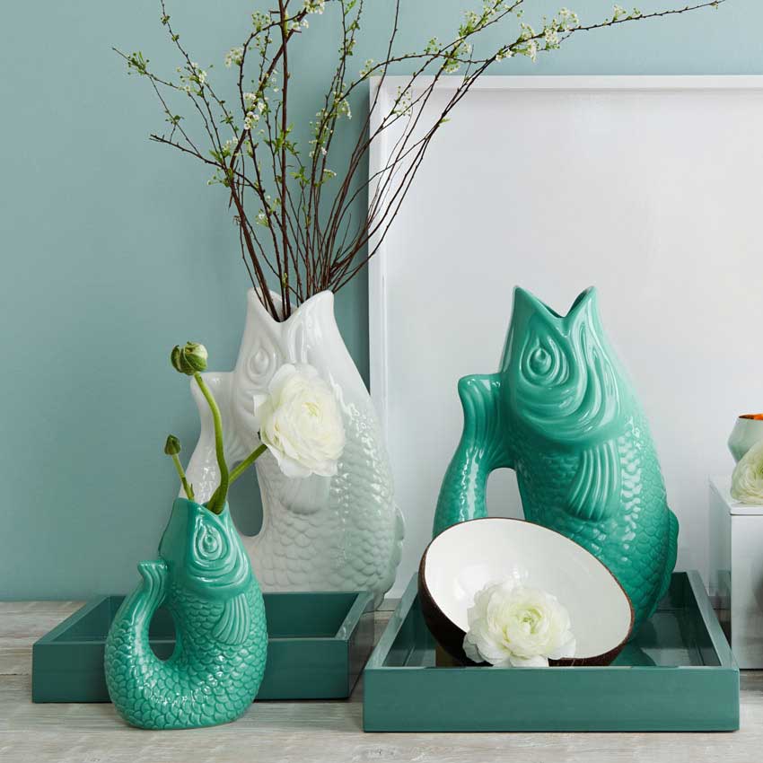 Blumenvasen „Monsieur Carafon“ von Gift Company – dekorative Fischvasen aus Keramik in Türkis und Weiß, stilvoll arrangiert mit Blumen und Ästen.