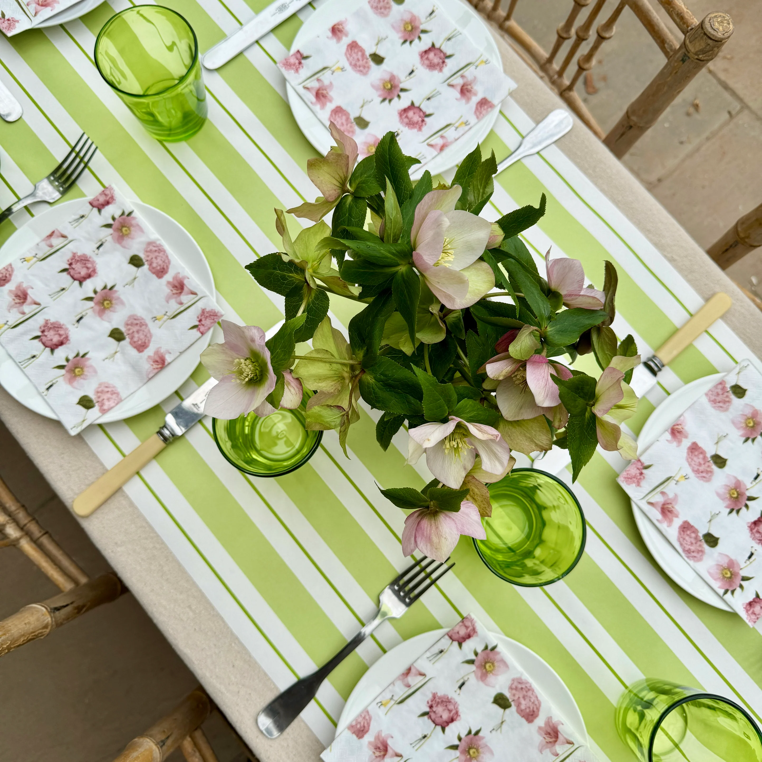 Frühlingshafte Tischdekoration mit „Pink Flowers“ Servietten von Laura Stoddart, floralen Motiven, grünen Gläsern und elegant gedecktem Tisch im Gartenstil.