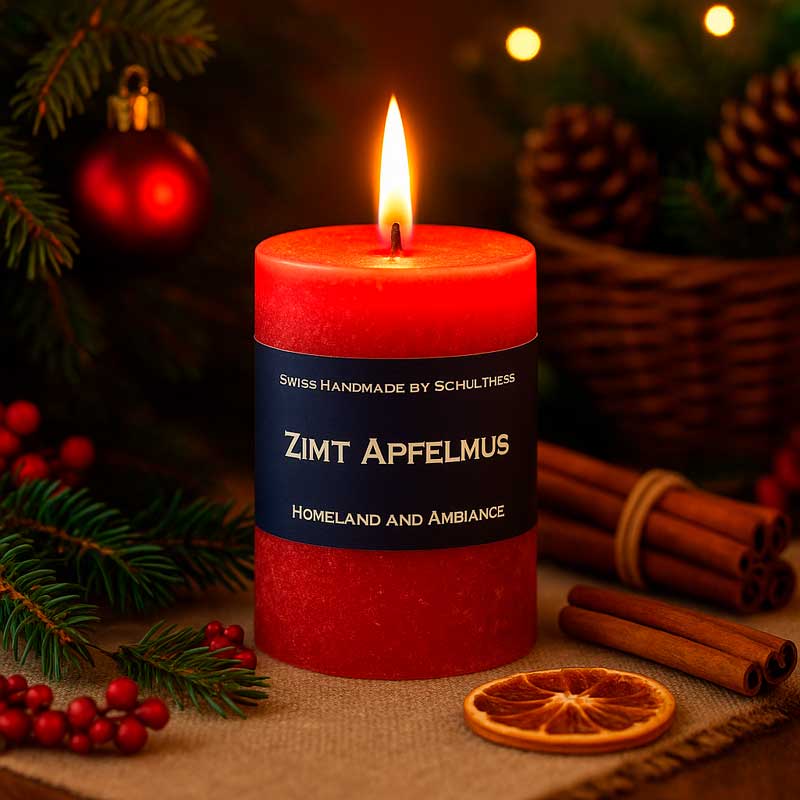 Brennende Schulthess Duftkerze Zimt Apfelmus aus der Homeland and Ambiance Kollektion, dekoriert mit Zimtstangen, getrockneten Orangenscheiben, Tannenzweigen und roten Beeren – warme, weihnachtliche Atmosphäre mit festlichem Duft.