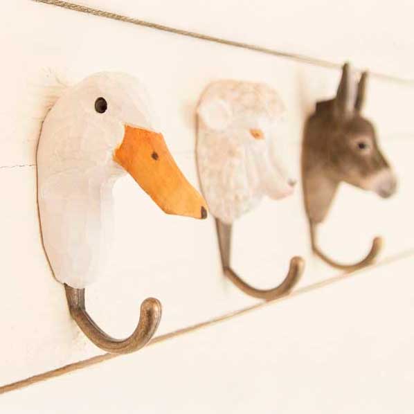 Drei handgeschnitzte Wandhaken aus Holz von Wildlife Garden in Tierform – Ente, Schaf und Esel. Die naturgetreuen Haken sind an einer hellen Holzwand befestigt und wirken rustikal und dekorativ.
