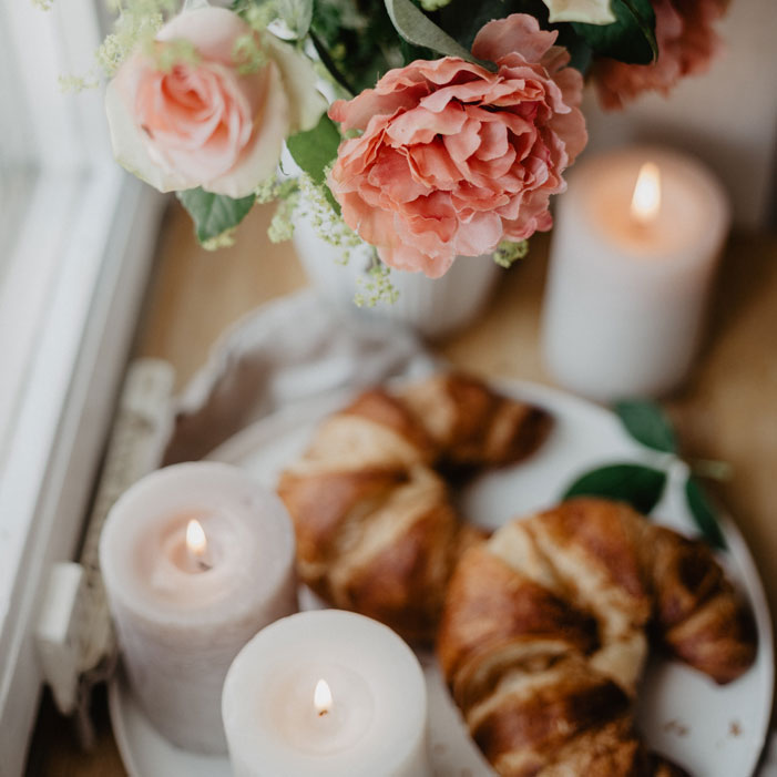 Gemütliche Szene mit brennenden Schulthess Kerzen, Croissants und Blumen – stimmungsvolle Deko im Schulthess Sale bei Lebenswerte