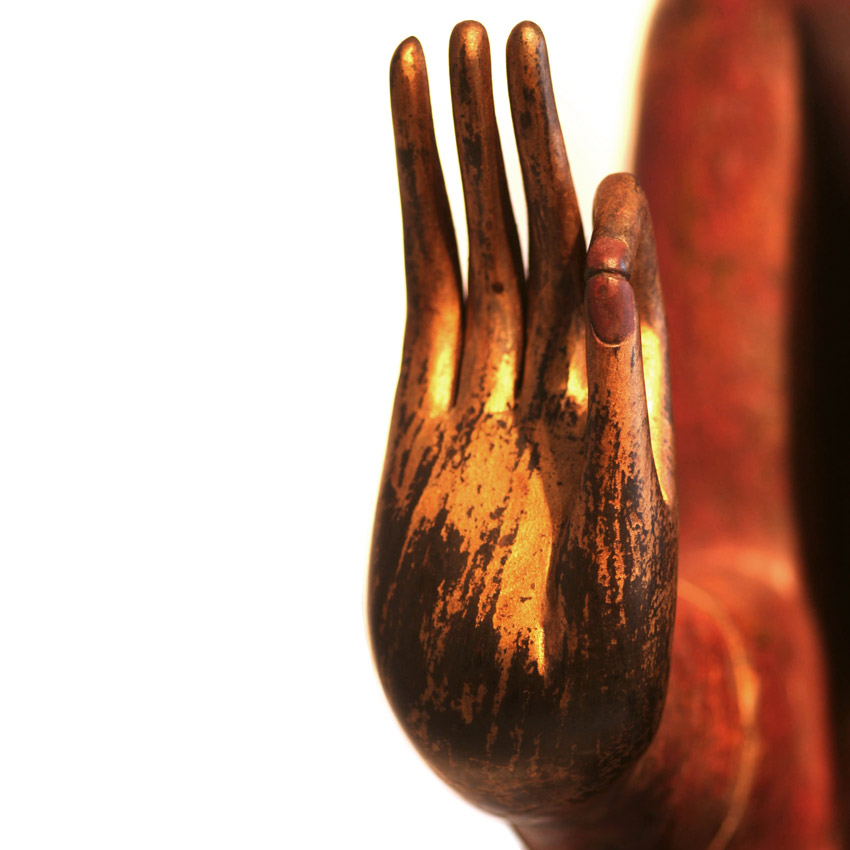 Detailansicht der erhobenen Hand eines großen roten Buddha, vergoldete Oberfläche mit Patina, Symbol der Segensgeste und Handwerkskunst.