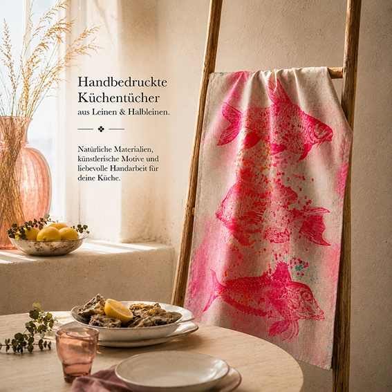 Editorial-Inszenierung eines handbedruckten Frohstoff Atelier Unique Geschirrtuchs mit pinken Fischmotiven aus Leinen und Halbleinen in warmer mediterraner Interior-Atmosphäre.