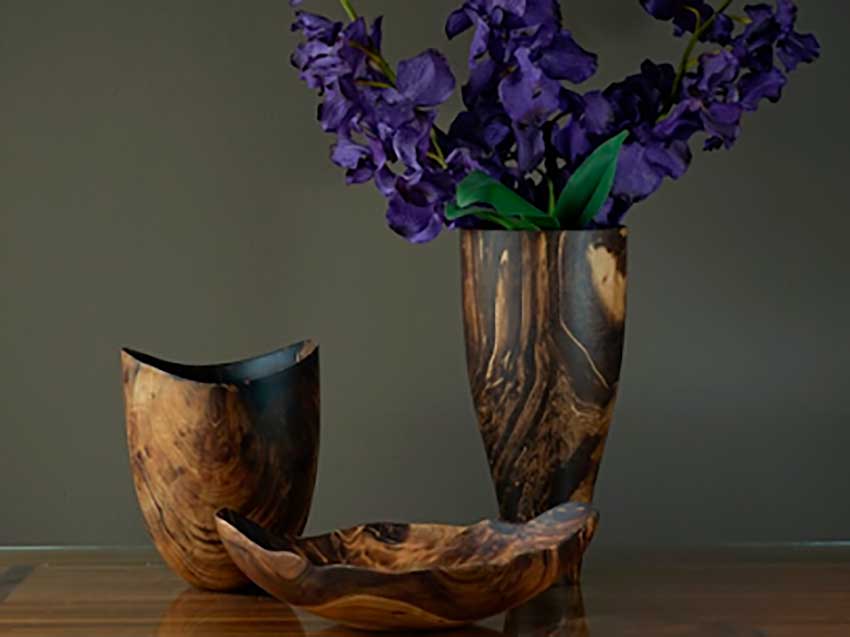 Dekorative Schalen und Vasen aus dunklem Mangoholz mit natürlicher Maserung, stilvoll mit violetten Blüten arrangiert – edles Wohnaccessoire aus Naturmaterial.