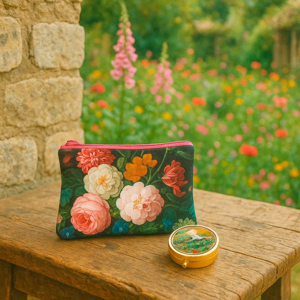 Beutel mit Blumenmotiv von De Heem und goldfarbene Pillendose im Garten, dekorativ auf Holztisch arrangiert – stilvolle Accessoires von Lebenswerte.
