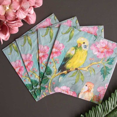 Vier PPD Servietten mit farbenfrohem Design „Perruches“, featuring gelbe und orangefarbene Wellensittiche auf blühenden Zweigen mit rosa Blumen – stilvolle Papierservietten für Frühlings- und Sommerdekoration.